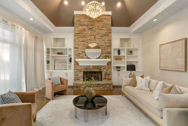 living room featuring built in shelves, vaulted ceiling, a chandelier, hardwood / wood-style floors, and a stone fireplace