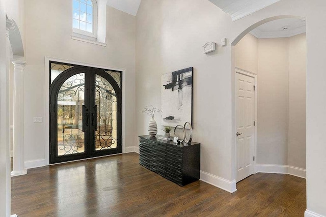 entrance foyer featuring french doors, dark wood-type flooring, a high ceiling, and ornamental molding