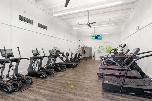 exercise room with ceiling fan, wood-type flooring, and a towering ceiling