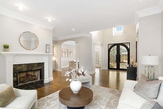 living room featuring ornate columns, a tile fireplace, french doors, dark hardwood / wood-style flooring, and ornamental molding