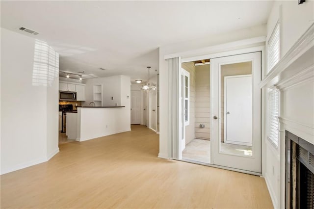 5638 River Heights Xing SE, Marietta, GA 30067 - unfurnished living room featuring baseboards, an inviting chandelier, a fireplace, visible vents, and light wood finished floors