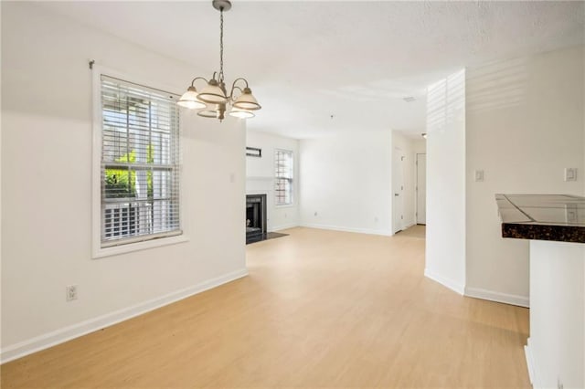 5638 River Heights Xing SE, Marietta, GA 30067 - unfurnished living room featuring a chandelier, light wood-style floors, a fireplace, and baseboards