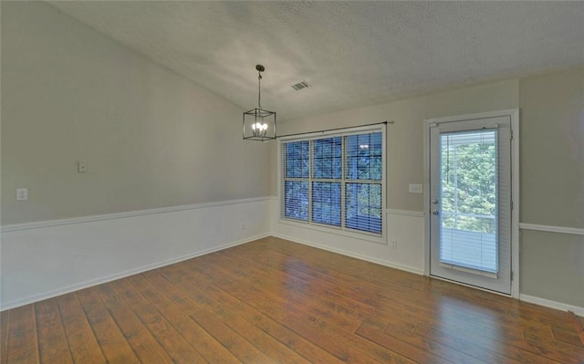 unfurnished dining area with visible vents, baseboards, a textured ceiling, hardwood / wood-style flooring, and a notable chandelier