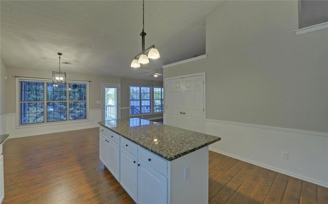 kitchen featuring white cabinets, dark wood-style floors, decorative light fixtures, a center island, and a notable chandelier