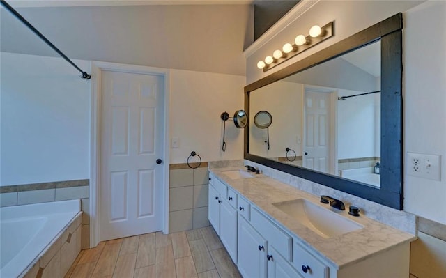 bathroom featuring tile walls, tiled tub, a sink, and double vanity