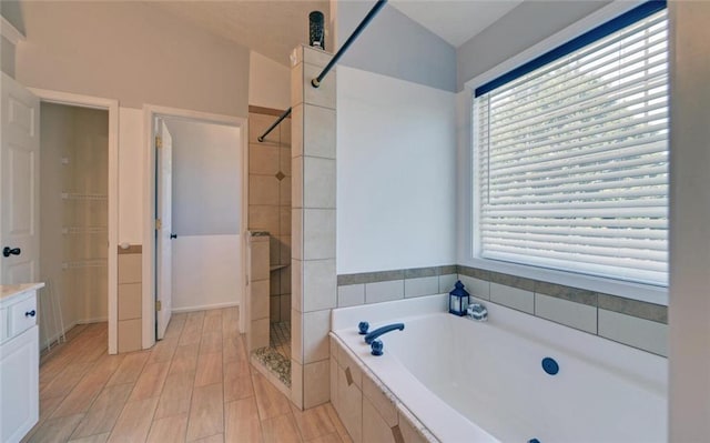 full bath with a garden tub, vanity, and tiled shower