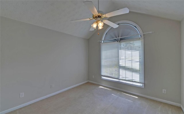 carpeted empty room with lofted ceiling, a ceiling fan, and baseboards