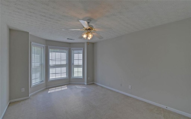 carpeted spare room with ceiling fan, baseboards, and visible vents