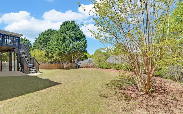 view of yard with a wooden deck, stairs, and fence