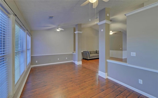 unfurnished room featuring a textured ceiling, wood finished floors, visible vents, and a ceiling fan