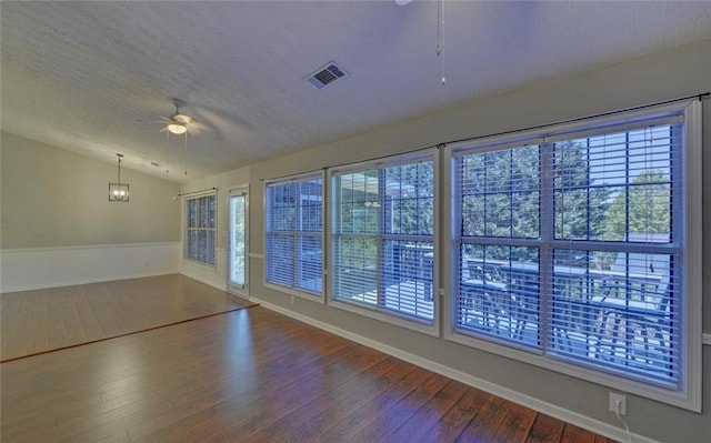 spare room with lofted ceiling, dark wood-style floors, visible vents, a ceiling fan, and baseboards