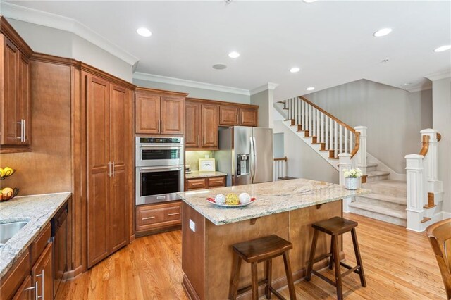 11259 Calypso Dr, Alpharetta, GA 30009 - kitchen with appliances with stainless steel finishes, ornamental molding, light wood-style flooring, a breakfast bar, and brown cabinets