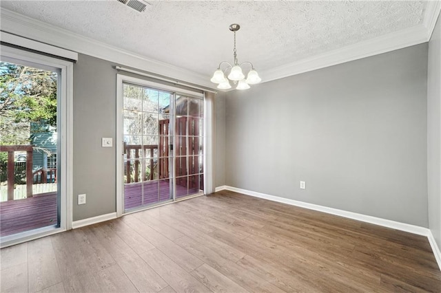 unfurnished room featuring a notable chandelier, wood finished floors, visible vents, plenty of natural light, and crown molding