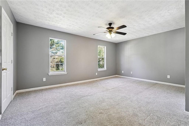 carpeted spare room featuring ceiling fan, a textured ceiling, and baseboards