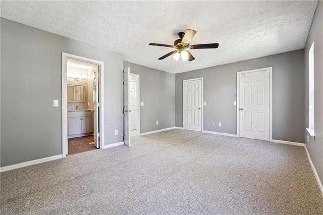 unfurnished bedroom with a textured ceiling, carpet floors, a ceiling fan, and baseboards