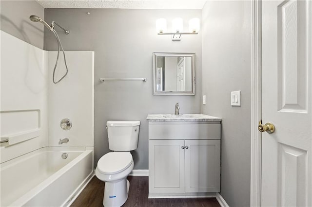 bathroom with toilet, wood finished floors, vanity, baseboards, and shower / bathing tub combination