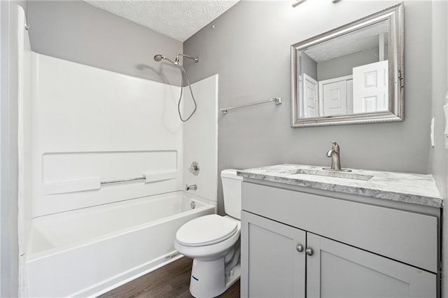 full bathroom with shower / washtub combination, toilet, a textured ceiling, vanity, and wood finished floors