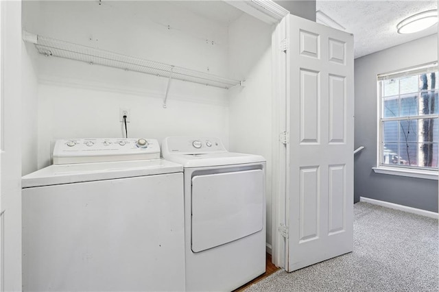 laundry room with light colored carpet, a textured ceiling, separate washer and dryer, laundry area, and baseboards