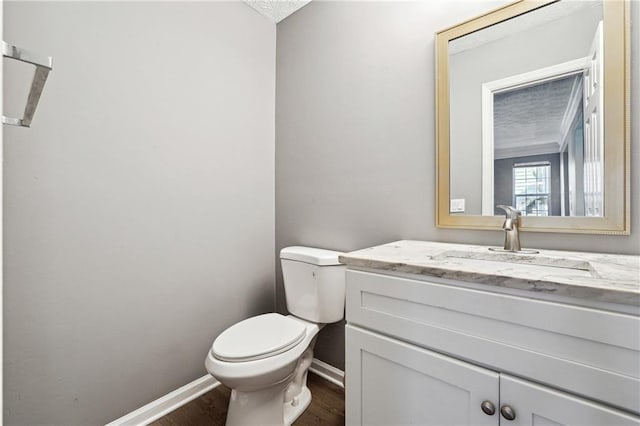 half bath featuring toilet, baseboards, wood finished floors, and vanity