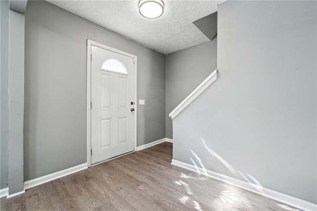 entryway featuring a textured ceiling, baseboards, and wood finished floors