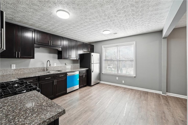 kitchen with light wood-style floors, freestanding refrigerator, a sink, dishwasher, and baseboards