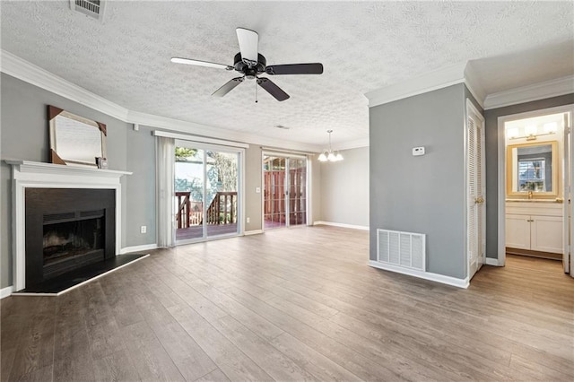 unfurnished living room with a fireplace with raised hearth, wood finished floors, visible vents, and crown molding