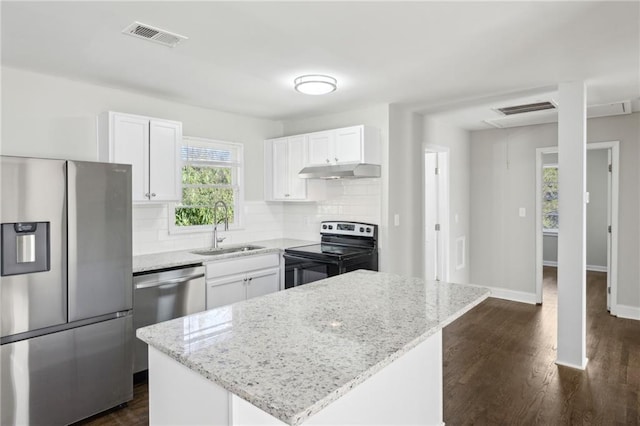 kitchen with light stone countertops, sink, stainless steel appliances, and a kitchen island