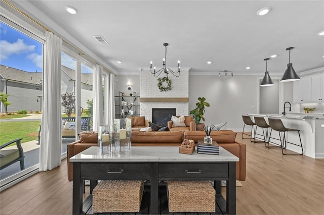940 Emmett Walk, Alpharetta, GA 30004 - living room with light wood finished floors, a brick fireplace, a chandelier, ornamental molding, and recessed lighting