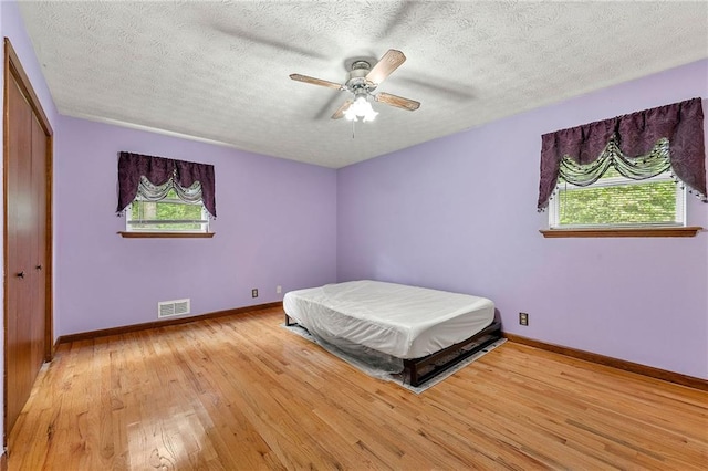 57 Fair Oaks Dr SE, Conyers, GA 30094 - bedroom featuring light wood-style floors, baseboards, a textured ceiling, ceiling fan, and a closet