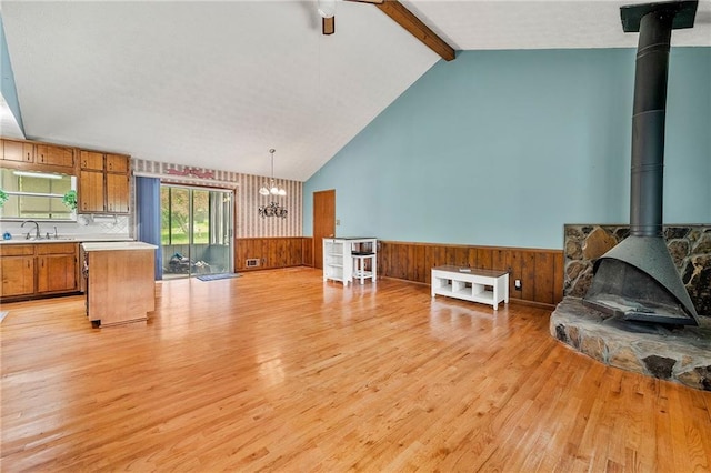 57 Fair Oaks Dr SE, Conyers, GA 30094 - living area with a wood stove, light wood-style floors, wainscoting, a chandelier, and wooden walls