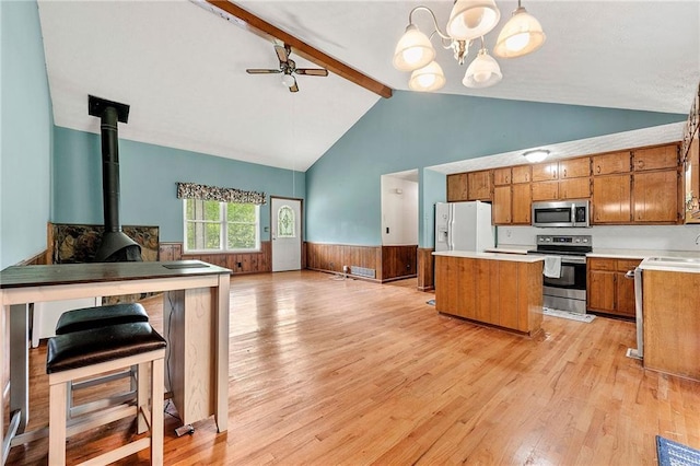 57 Fair Oaks Dr SE, Conyers, GA 30094 - kitchen featuring appliances with stainless steel finishes, brown cabinetry, wainscoting, a center island, and beamed ceiling