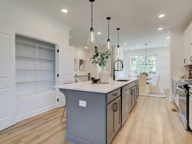 kitchen with sink, gray cabinetry, white cabinetry, appliances with stainless steel finishes, and an island with sink