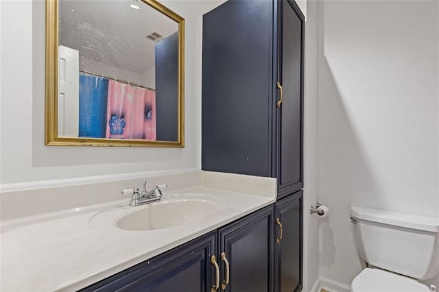 bathroom with toilet, vanity, and walk in shower