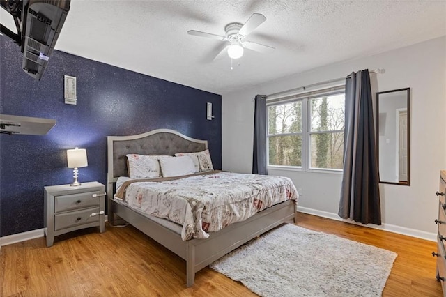 bedroom with light hardwood / wood-style floors, a textured ceiling, and ceiling fan