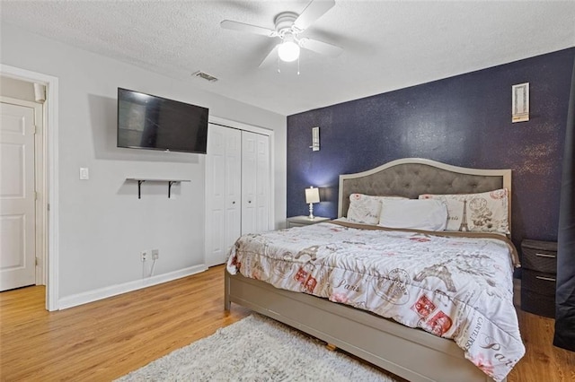 bedroom with hardwood / wood-style flooring, a textured ceiling, a closet, and ceiling fan