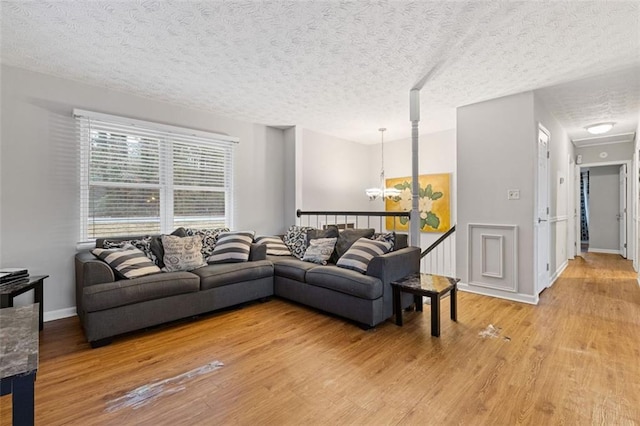 living room featuring a chandelier, light hardwood / wood-style floors, and a textured ceiling