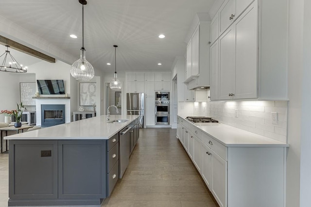 kitchen featuring a sink, open floor plan, white cabinetry, and stainless steel appliances