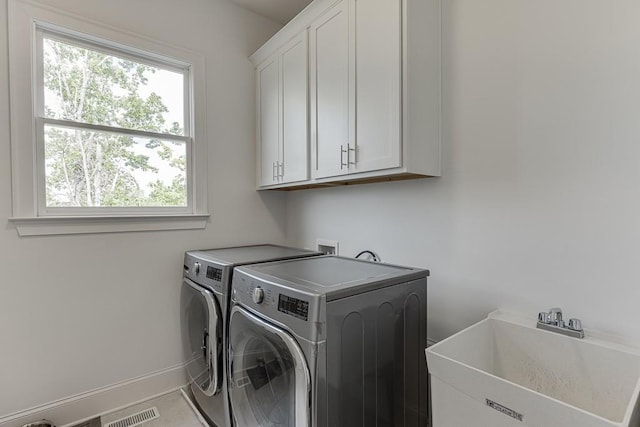 washroom featuring independent washer and dryer, visible vents, cabinet space, a sink, and baseboards