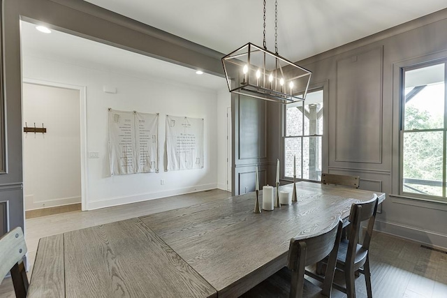dining area featuring baseboards, a chandelier, wood finished floors, and visible vents