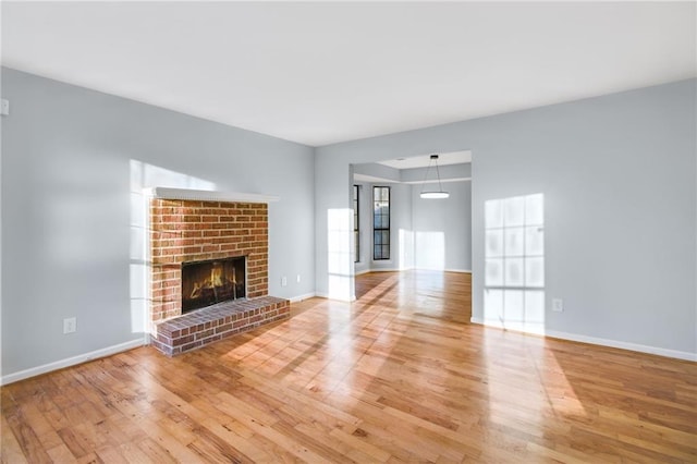 8914 Gardener Dr, Jonesboro, GA 30238 - unfurnished living room featuring wood finished floors, a brick fireplace, and baseboards
