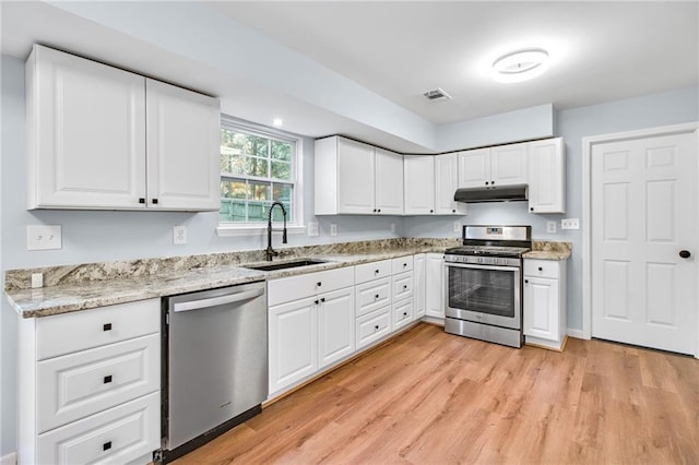 8914 Gardener Dr, Jonesboro, GA 30238 - kitchen with appliances with stainless steel finishes, a sink, under cabinet range hood, light wood-type flooring, and white cabinetry