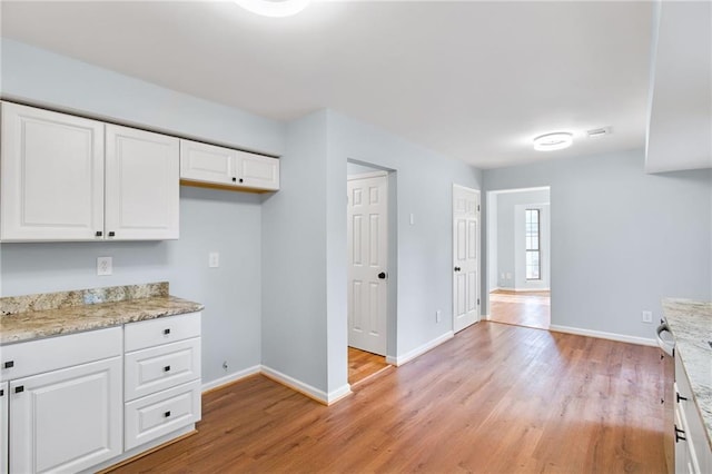 8914 Gardener Dr, Jonesboro, GA 30238 - kitchen featuring light wood finished floors, baseboards, white cabinets, and light stone counters
