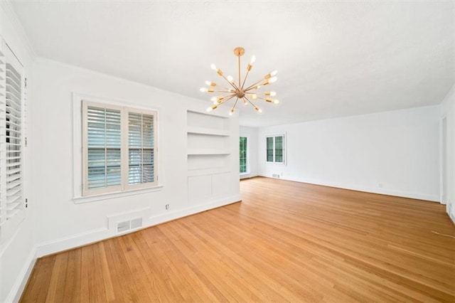 unfurnished living room featuring light wood-type flooring, a chandelier, and built in shelves