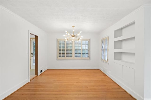 unfurnished dining area with built in shelves, crown molding, an inviting chandelier, a textured ceiling, and light wood-type flooring