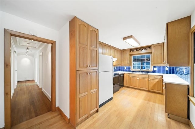 kitchen with sink, backsplash, white refrigerator, light wood-type flooring, and stainless steel electric range