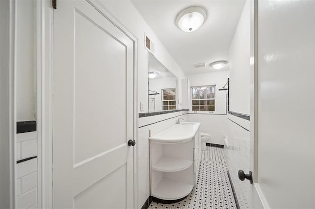 bathroom with tile patterned floors, toilet, tile walls, and vanity