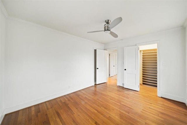 unfurnished bedroom featuring crown molding, ceiling fan, light hardwood / wood-style floors, and a closet