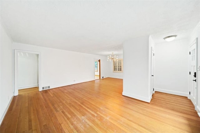 unfurnished living room with light wood-type flooring and a notable chandelier