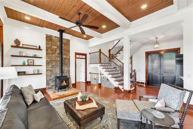 living room with dark hardwood / wood-style flooring, wooden ceiling, beam ceiling, a wood stove, and ceiling fan