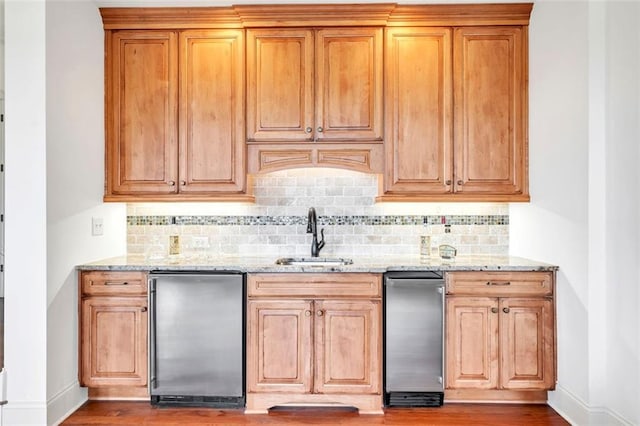 kitchen with sink, dark wood-type flooring, tasteful backsplash, and light stone countertops